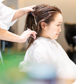 シャンプー後、カット台で髪を整えてもらっている女性の画像 